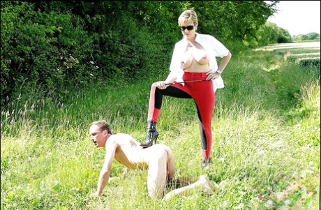 Lusty mature lady in sunglasses disciplines her man slave outdoors